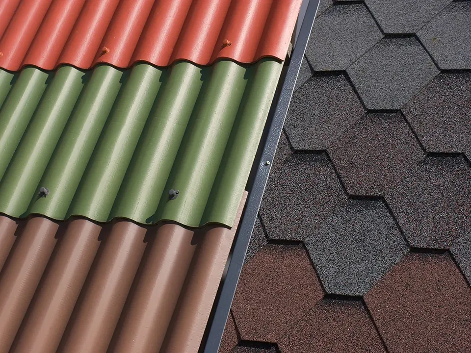 Red and green corrugated roofing panels beside brown asphalt shingles