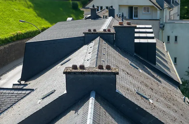Dark slate roof with several brick chimneys seen from above