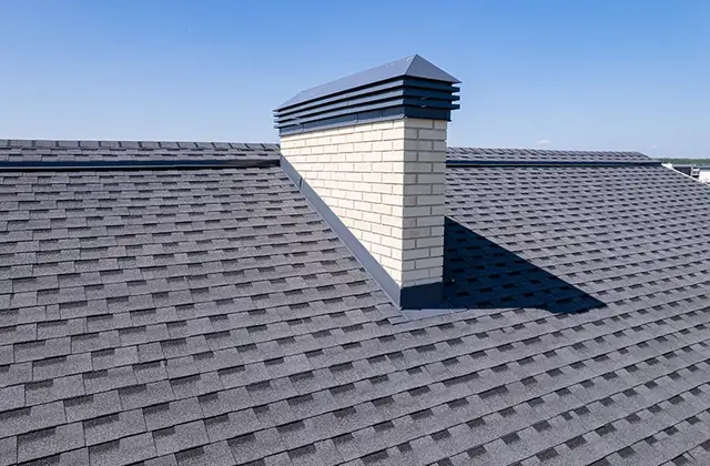 Gray asphalt shingle roof with a white chimney cap